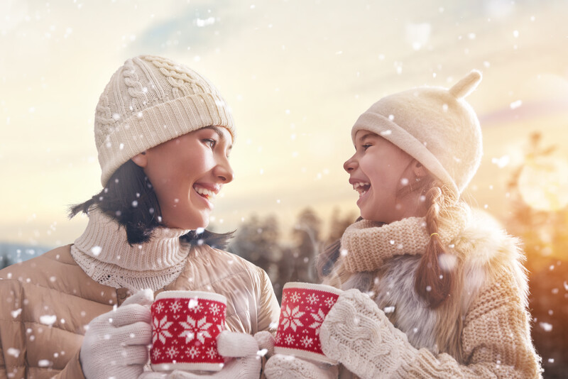 mom and daughter drinking hot chocolate on a snowy day