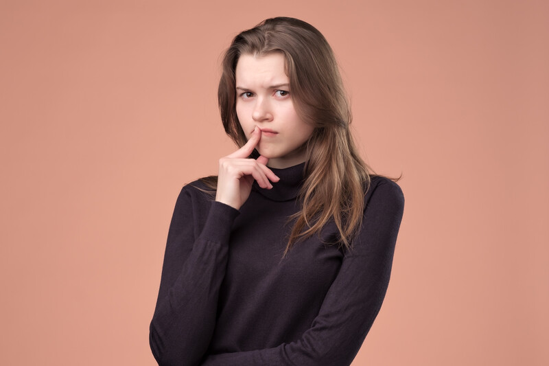 worrying memories & experiences away: pensive looking young woman in brown sweater