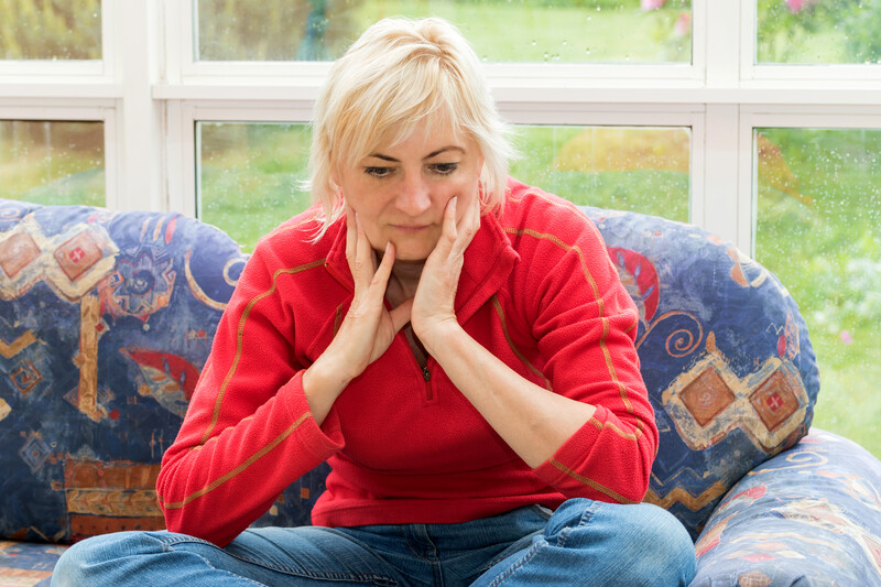 post-traumatic stress after divorce: depressed blonde woman sitting on red couch