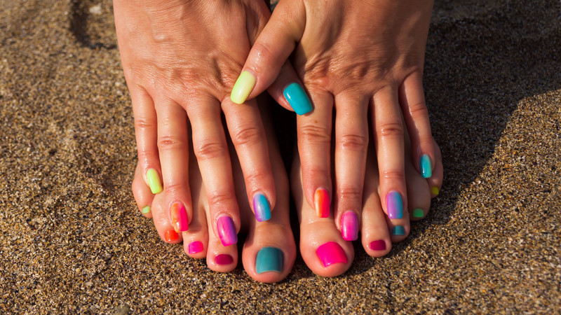 self-care priorities: woman's hands and feet with color nail polish