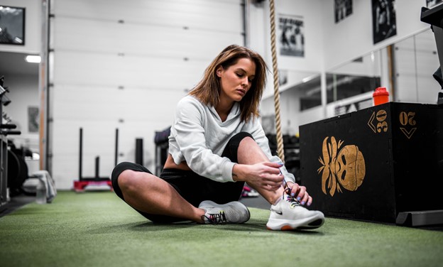 benefits of exercise during divorce: woman in workout clothes sitting on a gym floor