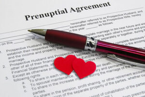 prenups and remarriage: prenuptial agreement with pen and two red hearts sitting on top of it