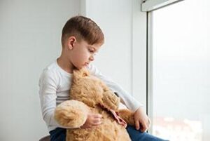 child sexual abuse: sad boy cuddles teddy bear